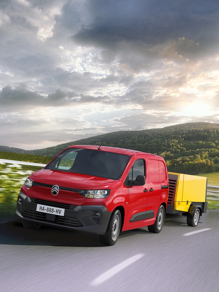 Berlingo Van die een aanhanger trekt op een landelijke weg, met Trailer Stability Control voor stabiel en veilig trekken.