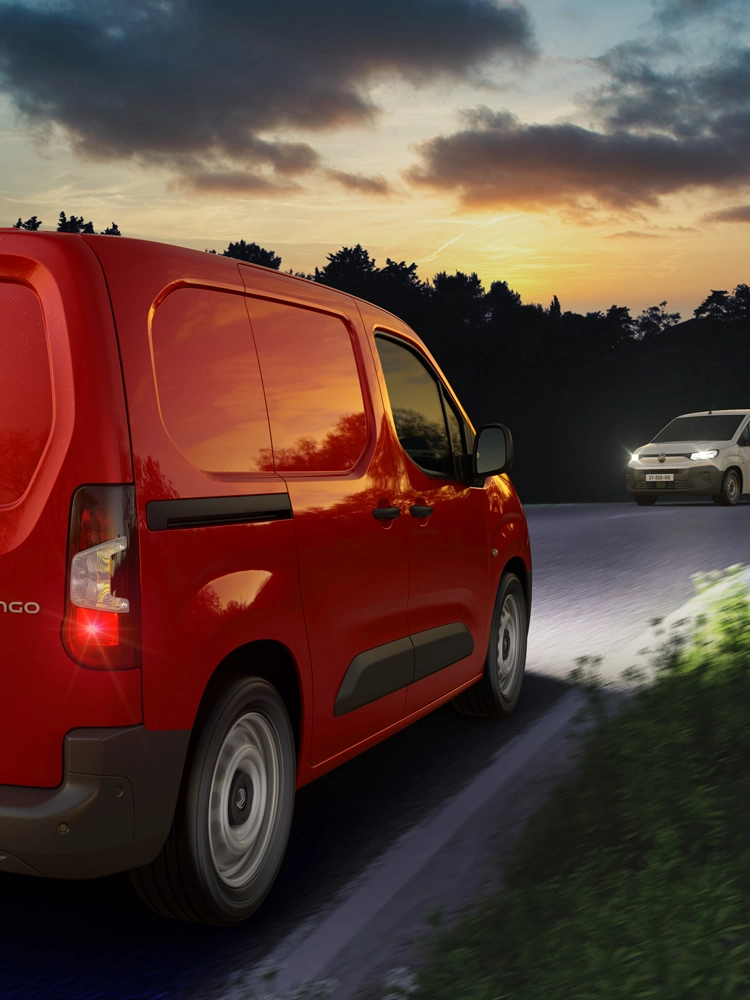 Rode Berlingo Van rijdend in de nacht op een landelijke weg, waarbij automatische grootlichtassistent tegemoetkomend verkeer detecteert en de verlichting aanpast.