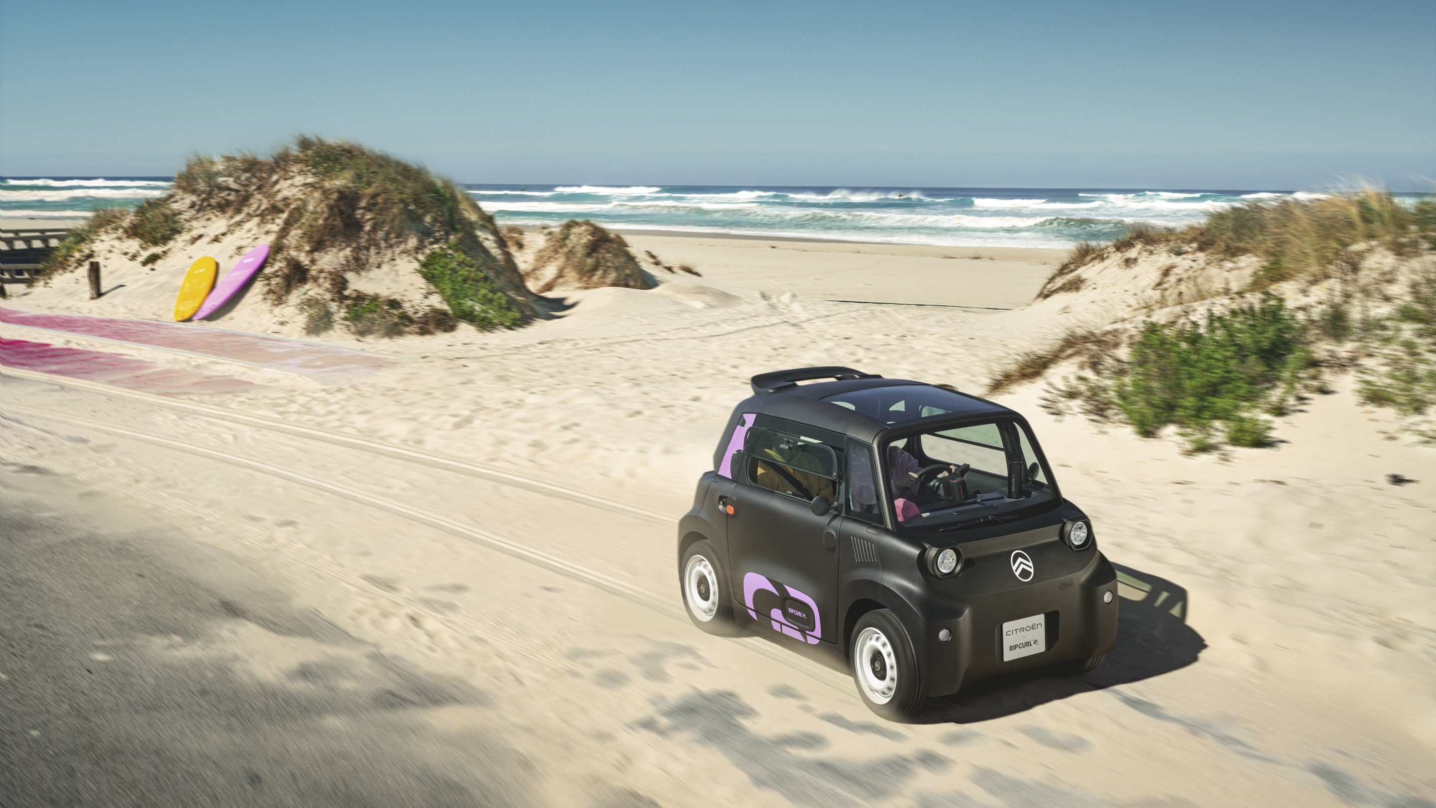 Driekwart vooraanzicht van de Citroën Ami x Rip Curl in actie, elektrische auto zonder autorijbewijs, als illustratie van vrijheid in de stad.
