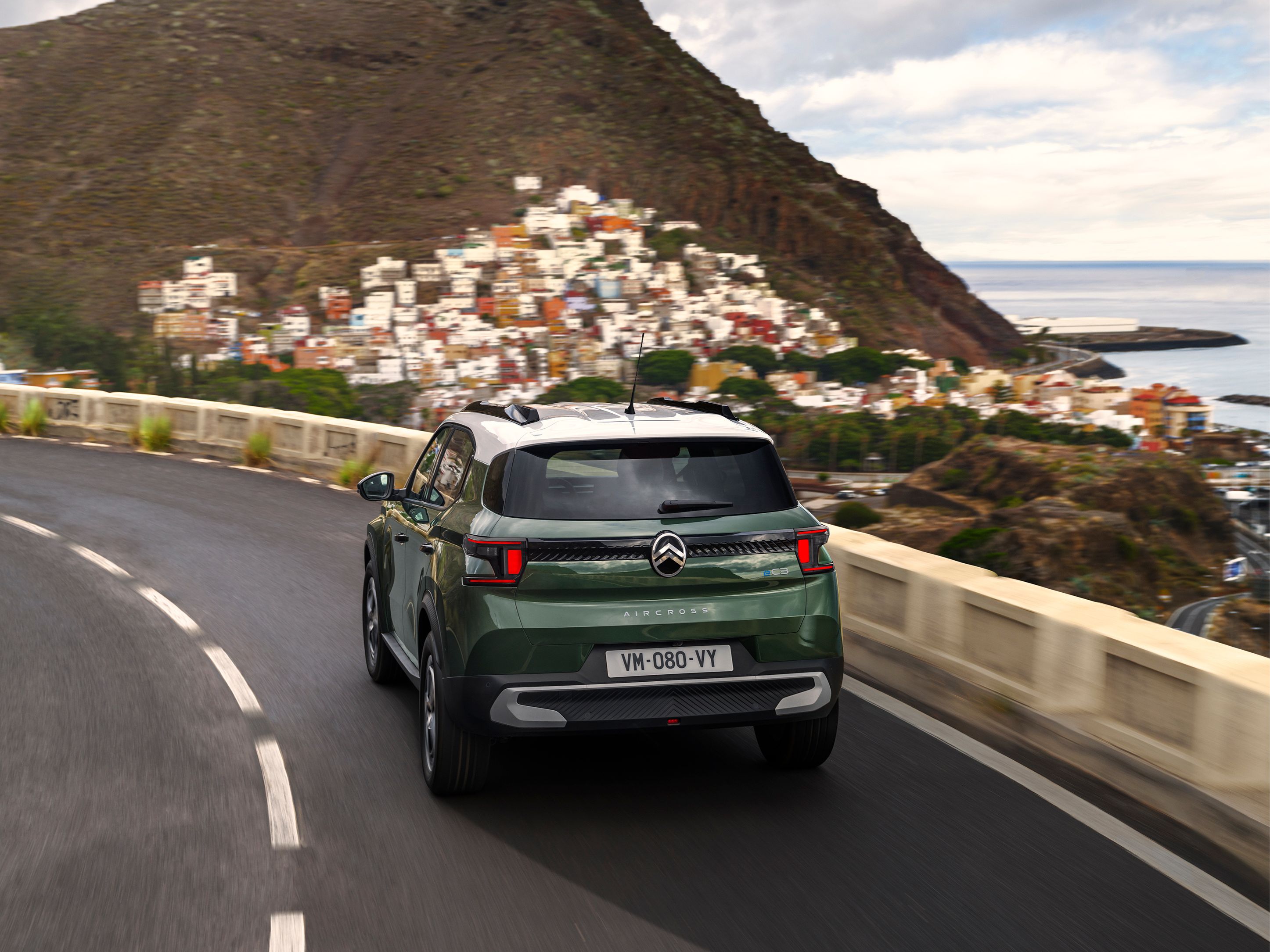Nieuwe C3 Aircross Driekwart achteraanzicht rijdend van de Citroën C3 Aircross SUV op een kustweg voor zelfverzekerde, soepele en betaalbare dagelijkse mobiliteit.