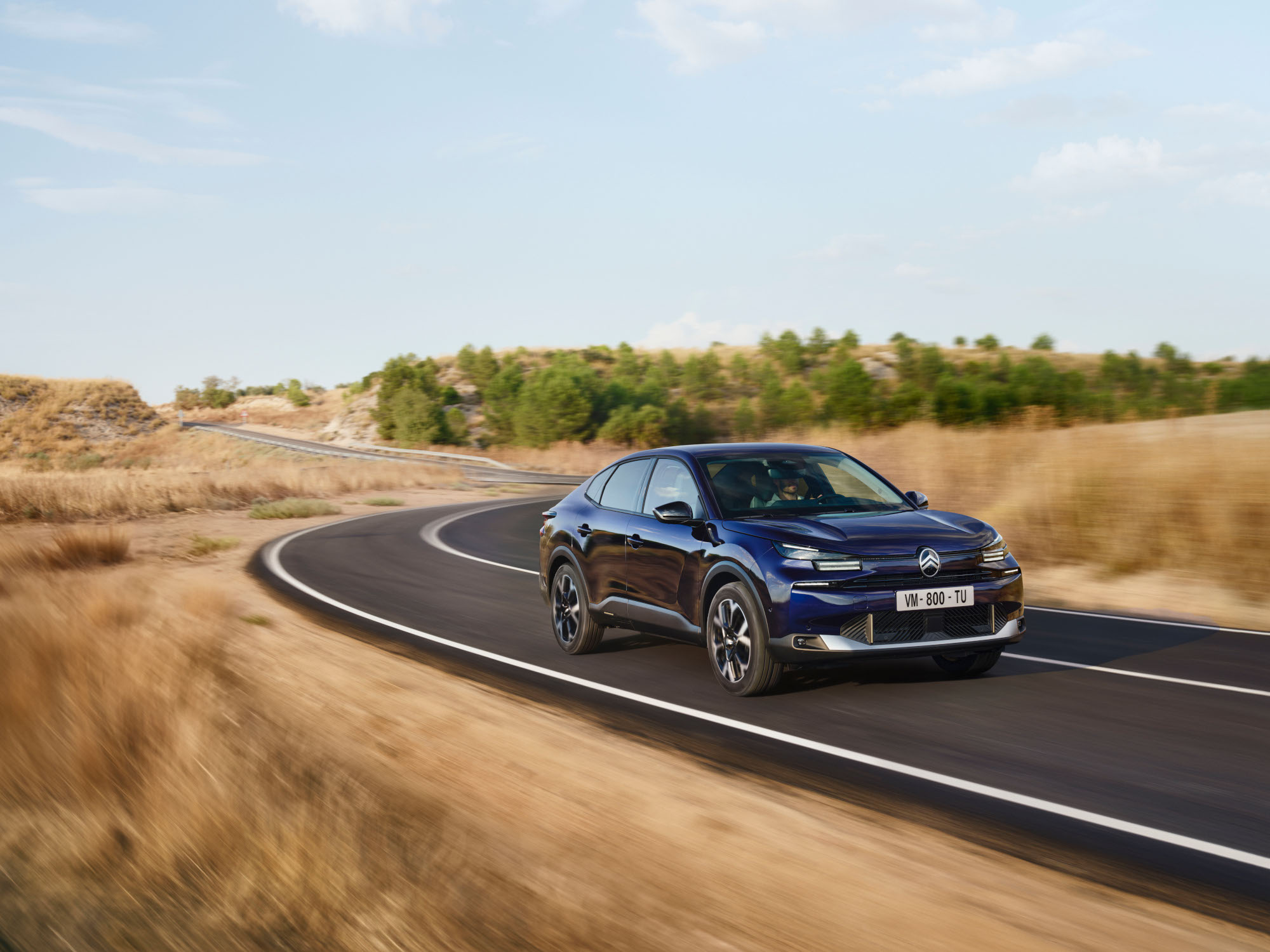 Driekwart vooraanzicht rijdend van de Citroën ë‑C4 X met wendbaar fastback‑design voor zelfverzekerde en betaalbare mobiliteit.