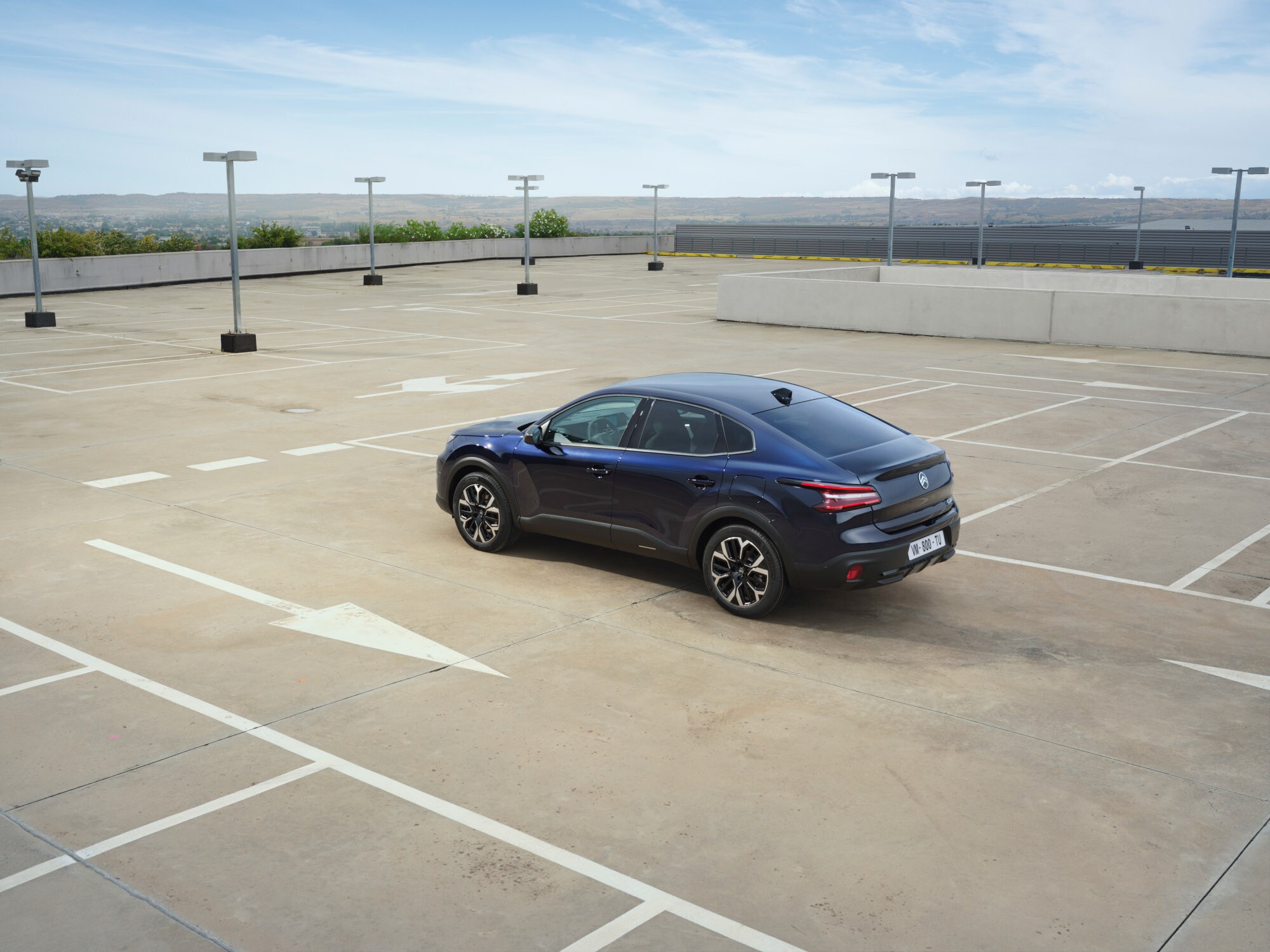 Driekwart achteraanzicht rijdend van de Citroën ë‑C4 X met moderne fastback‑stijl voor efficiënte en betaalbare mobiliteit.