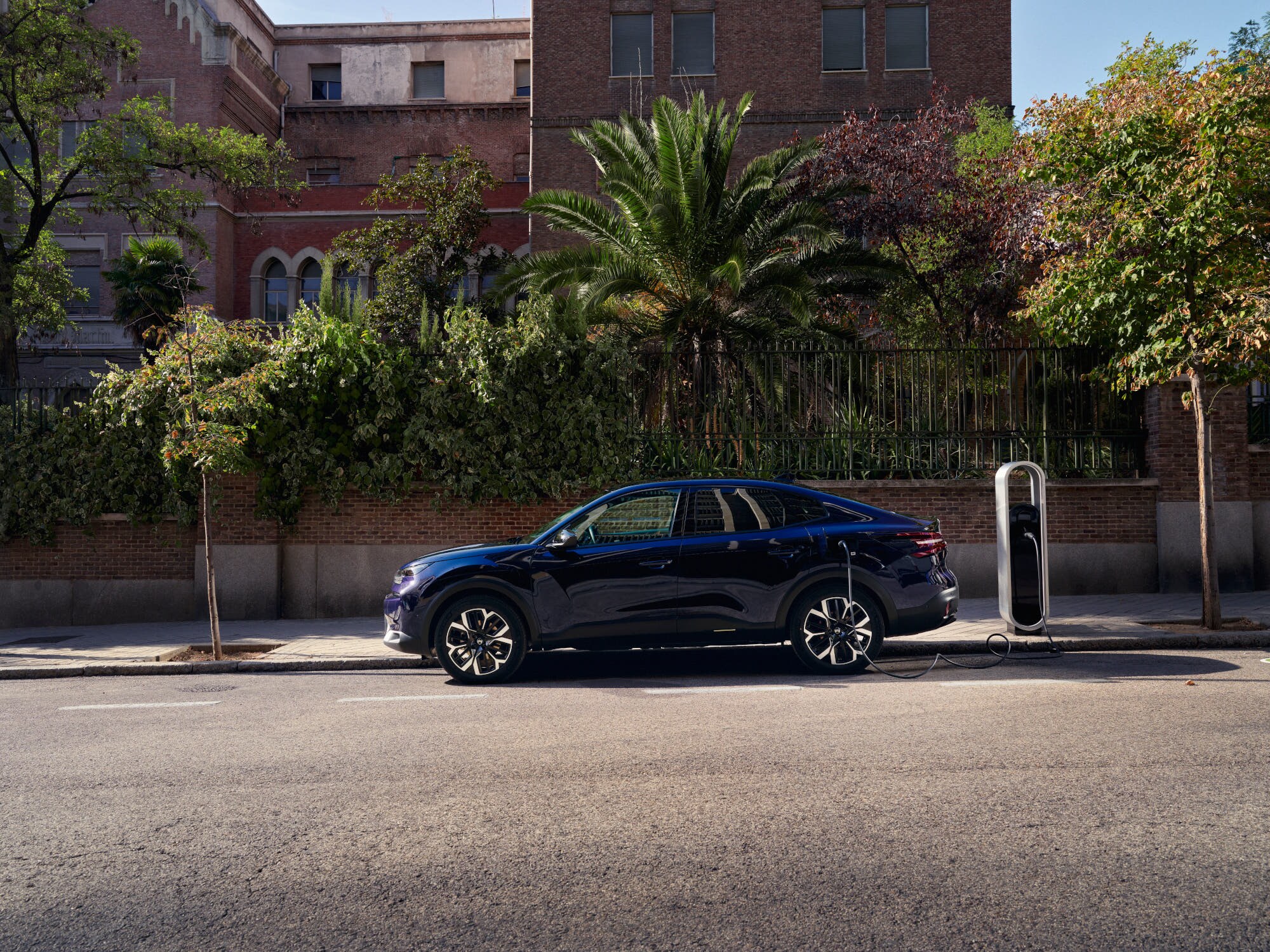 Zijaanzicht van de elektrische fastback Citroën ë‑C4 X tijdens straatladen, met nadruk op gemakkelijke en betaalbare stedelijke mobiliteit.